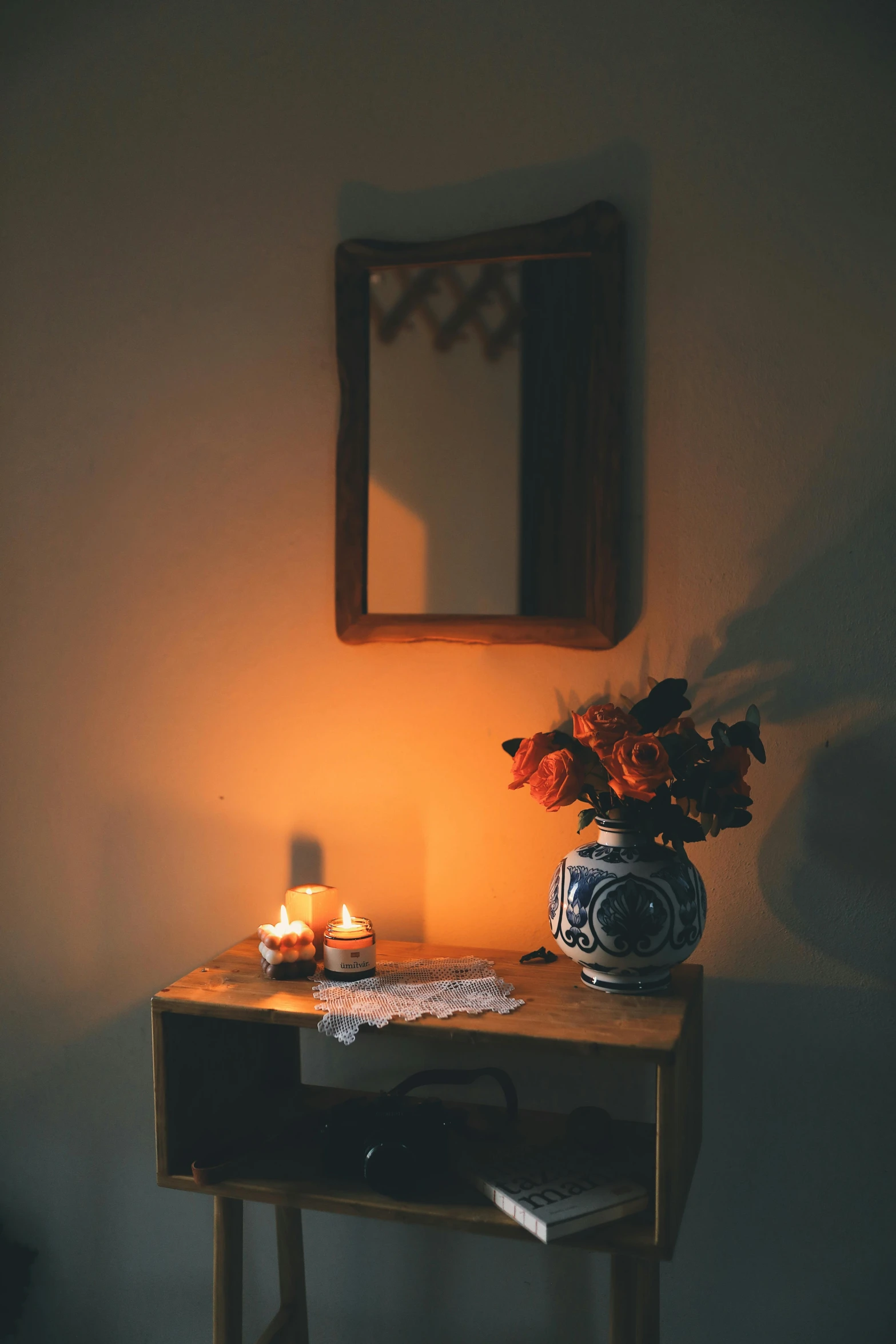 a table with flowers on it and a candle lit mirror above
