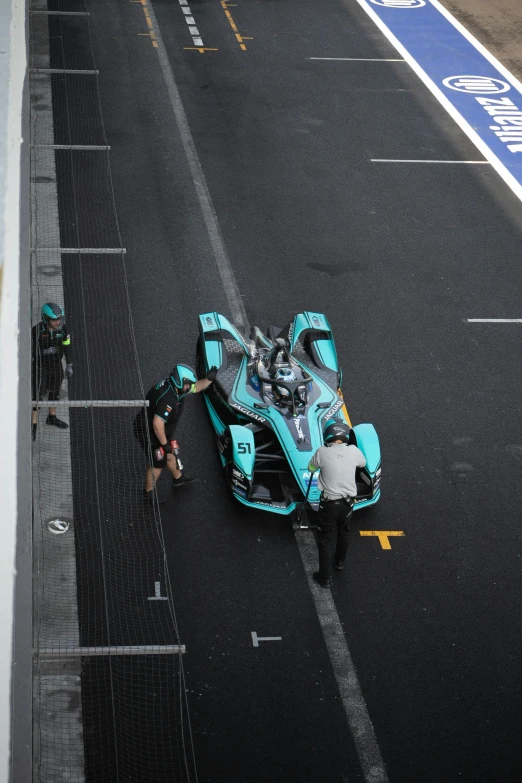 a blue race car is towed by mechanics
