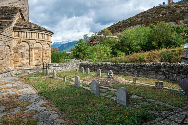 an old brick building with some graves sitting in the grass