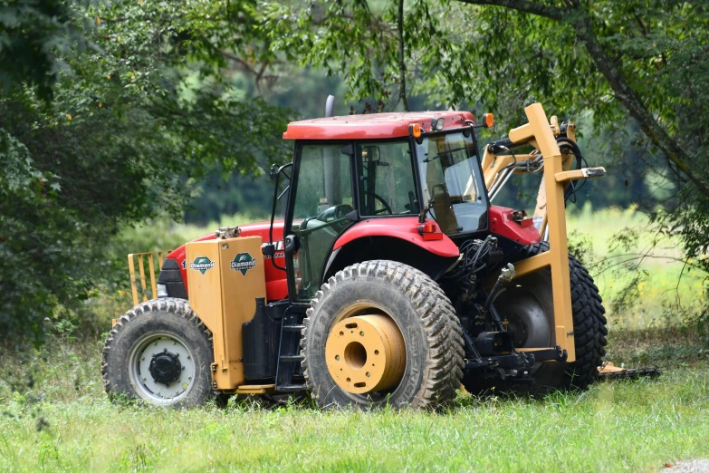 a red tractor is parked in the grass