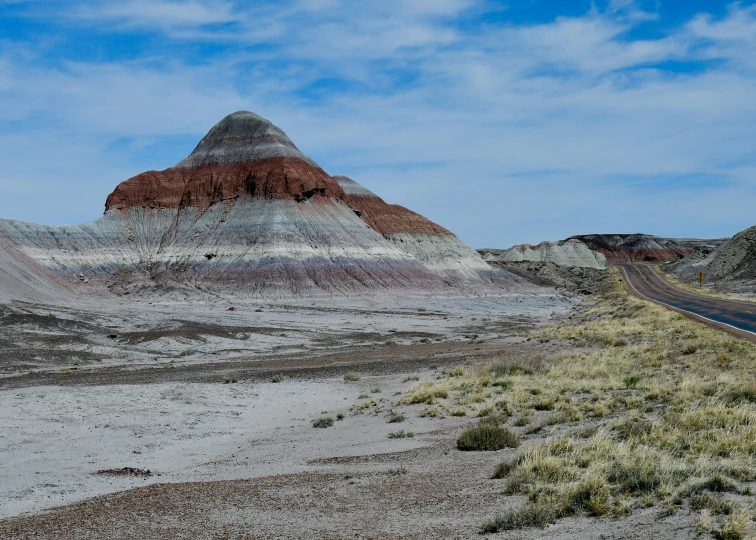 the road runs along the edge of a hill with many colored rocks on it