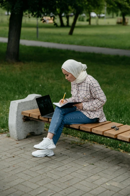a person sitting on a wooden bench writing