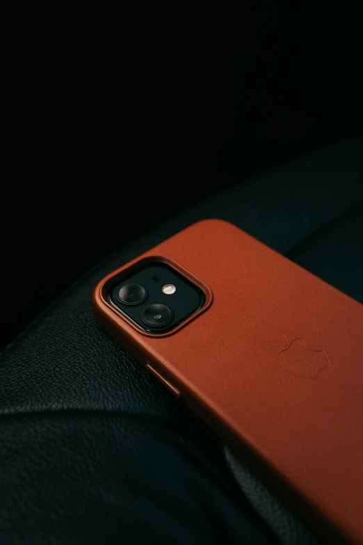 the iphone 11 is resting on top of a leather cushion