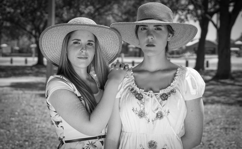 two women wearing straw hats posing for the camera