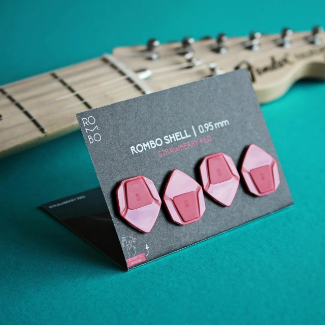 a set of four pink ear plugs in front of a guitar string