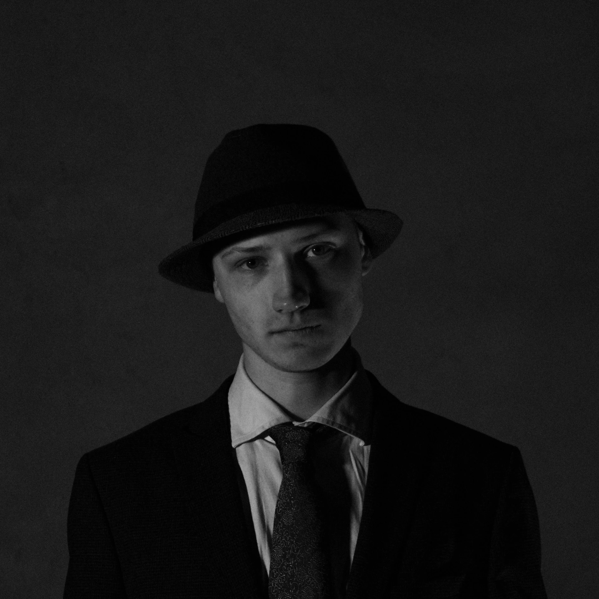 black and white portrait of a young man in a suit, tie and hat