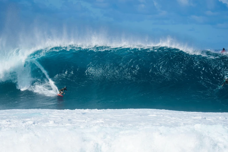 a man surfing in the water next to a huge wave