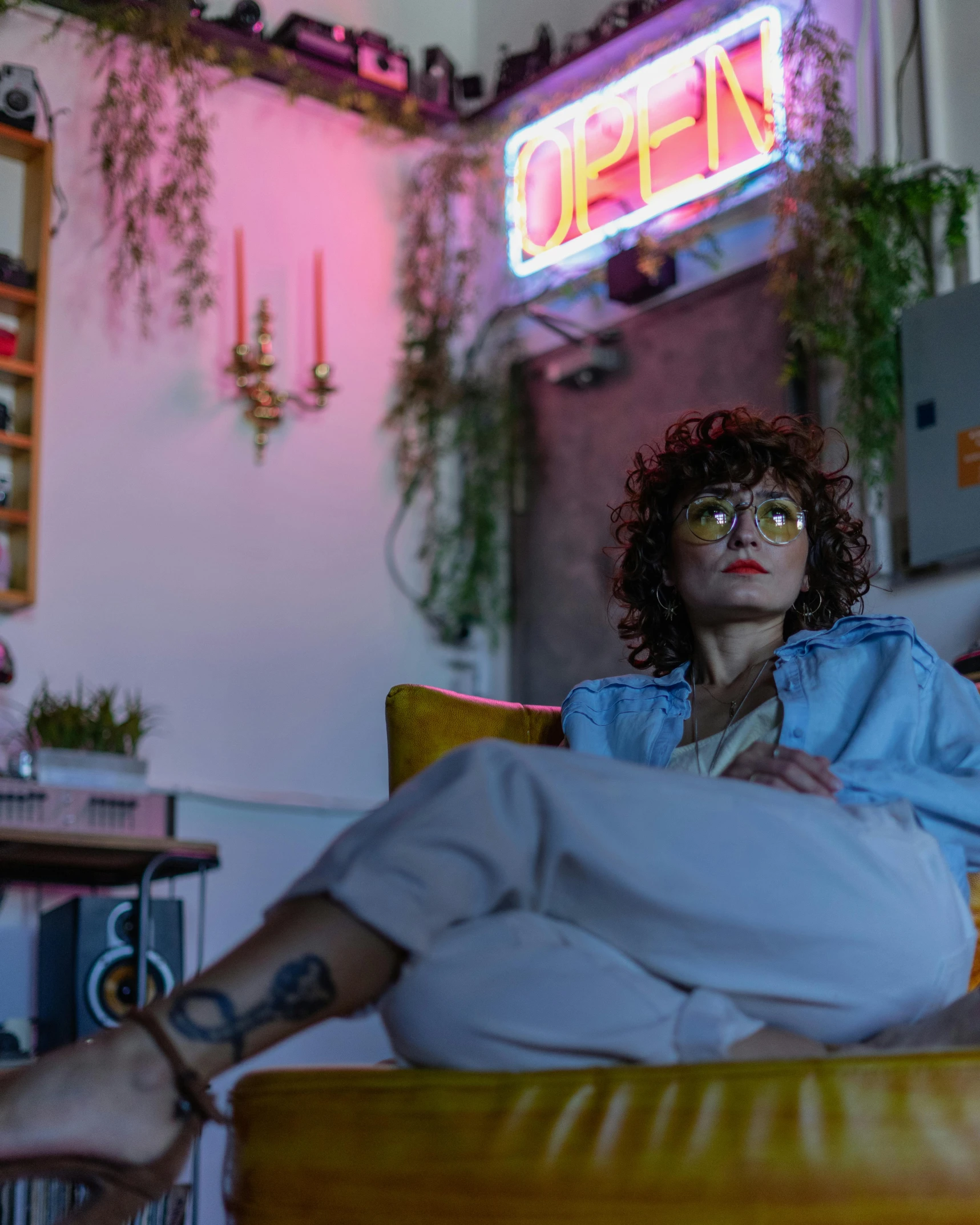 woman sitting in a yellow chair, under a neon sign above