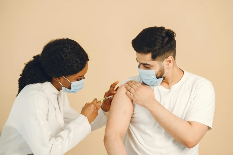 the woman is helping the man put on a surgical mask