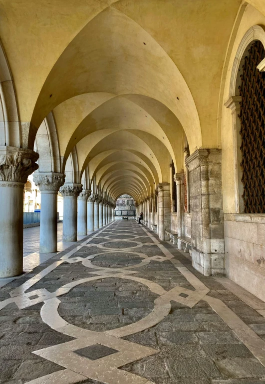 an empty walkway in an old building with arches and tiles