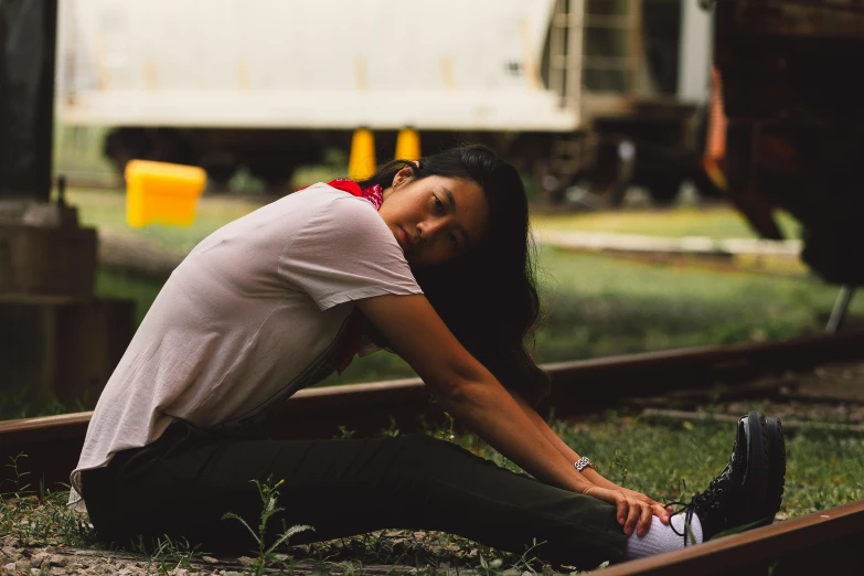 a woman sitting on railroad tracks near some chicken