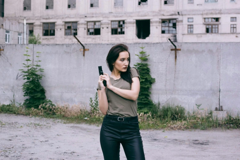 a woman holding a camera in her hand near an abandoned building