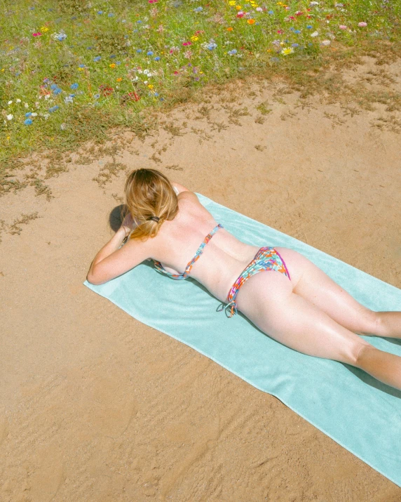 woman laying on a towel looking down in the sand