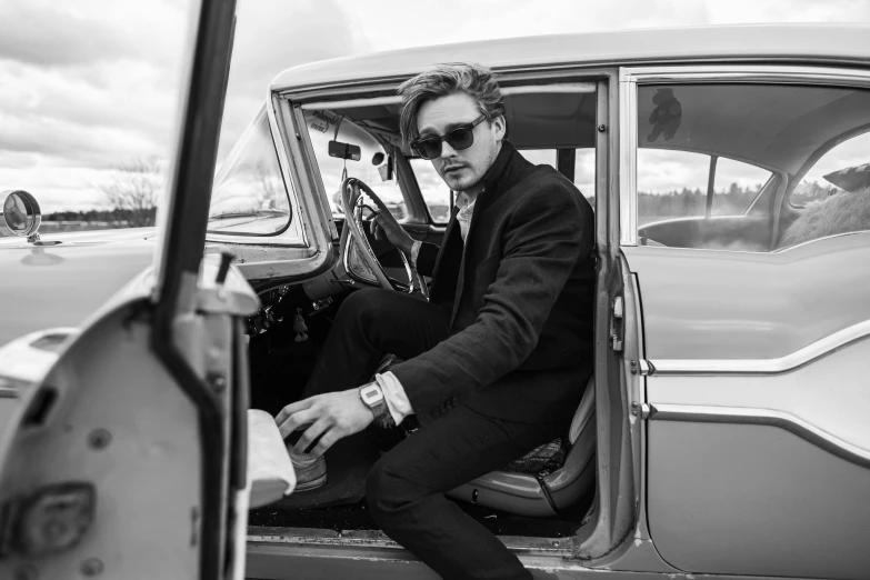 a man sits inside an antique car and stares into the window