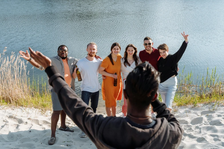 a group of people in a field of sand, some with their arms wide up and one person raising their hand