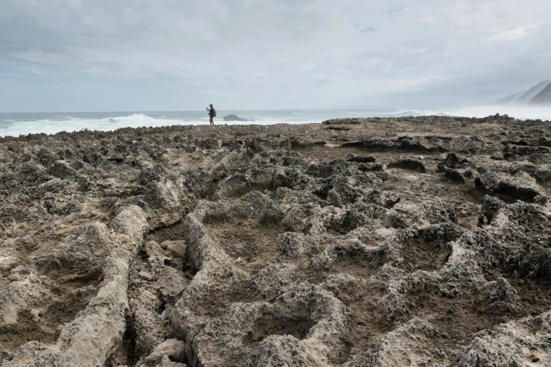 a man is standing on top of a rocky beach