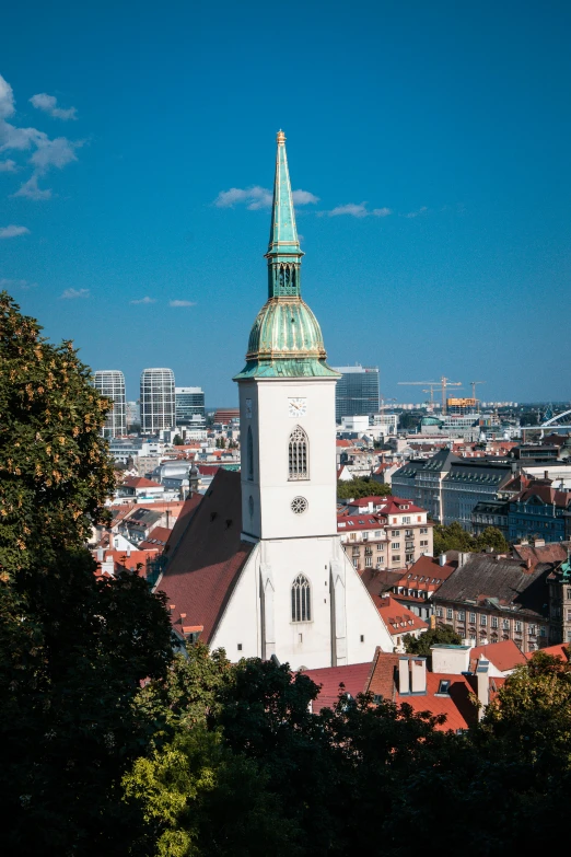 a tall white and green building sitting above trees