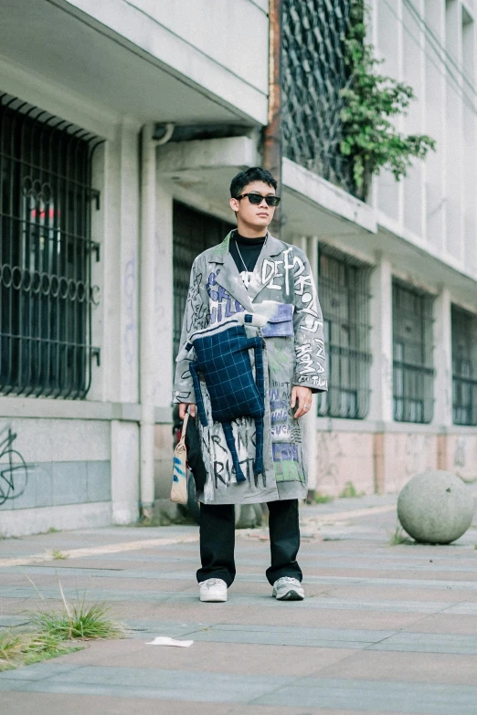 a man walking down a sidewalk with an empty bag on his shoulder