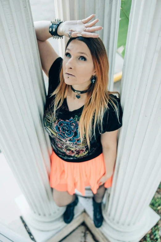 an attractive young woman with short hair and piercings posing behind columns