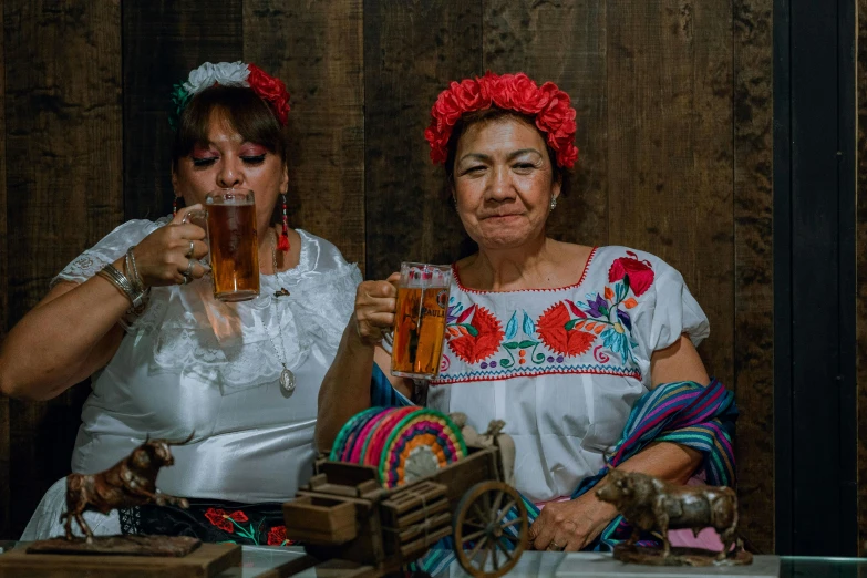 two women in costumes are tasting some beer