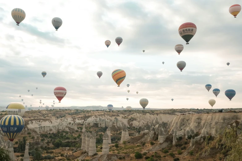 many colorful  air balloons flying over the top of a canyon