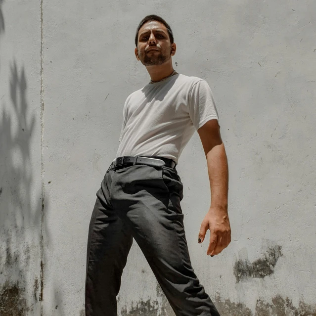 a man wearing sunglasses is skateboarding by a wall