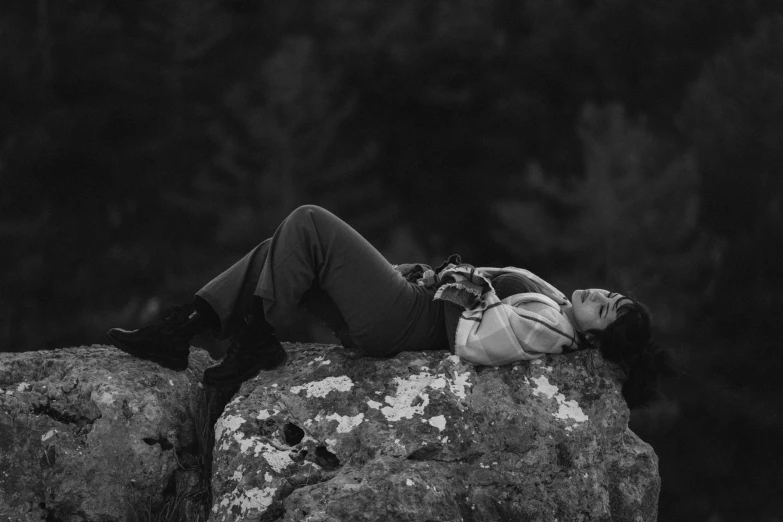 black and white pograph of woman lying on a rock