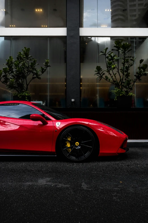 the red sports car is parked in front of a large building