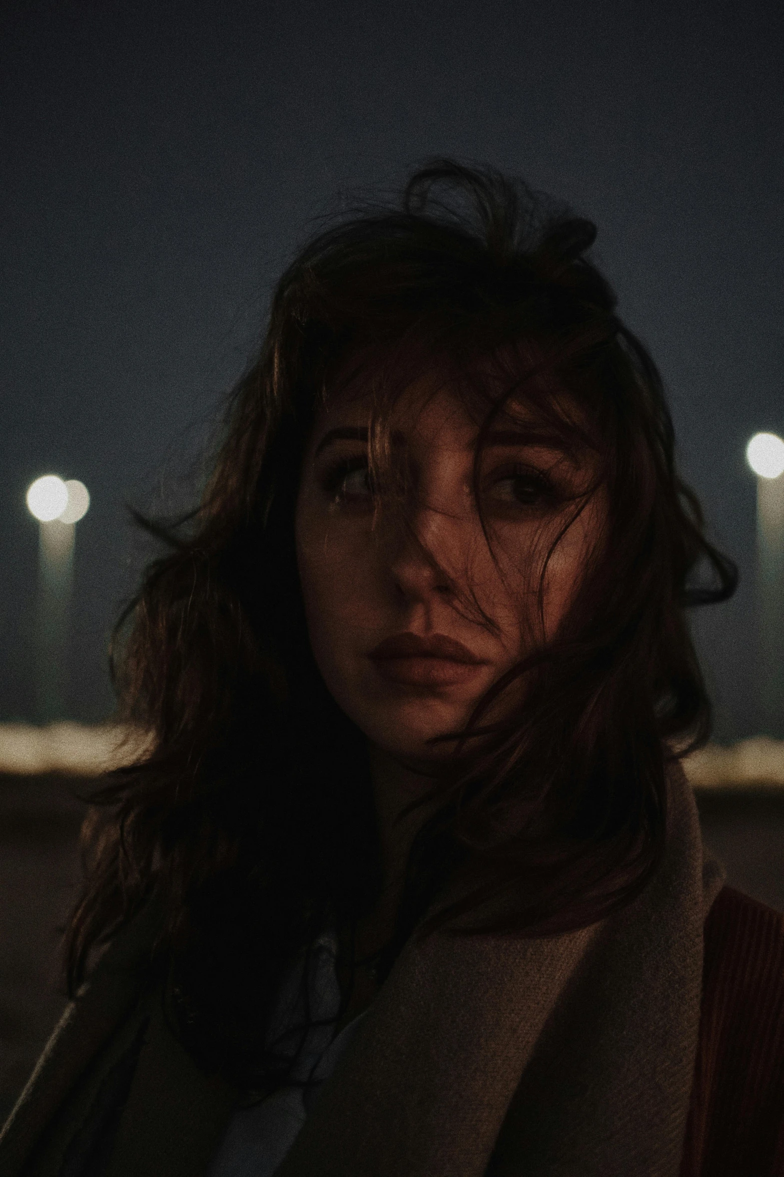 woman with eyes closed on night time near stadium