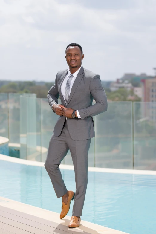 a man in a suit posing near a pool