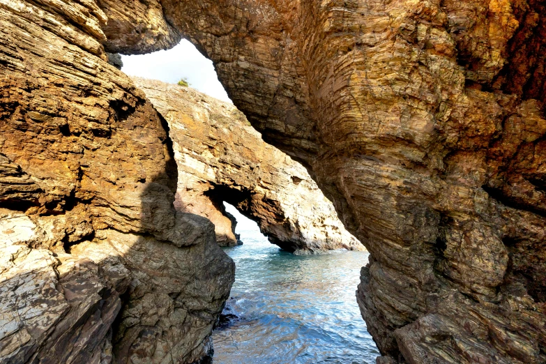 a rock formation near the ocean, with its cliff edge cut in half