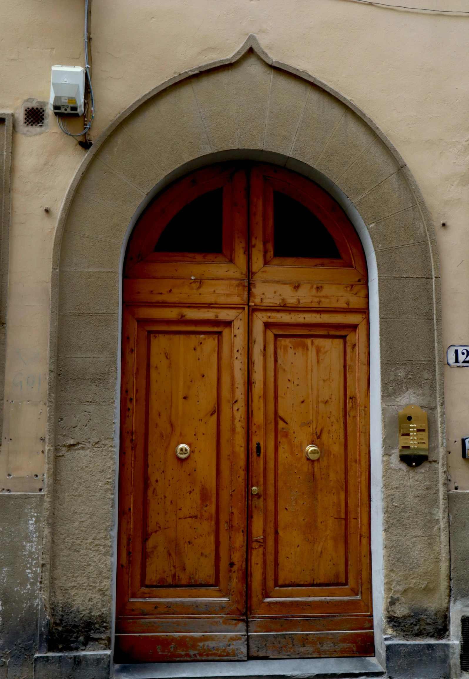 two brown doors in front of an arched entry