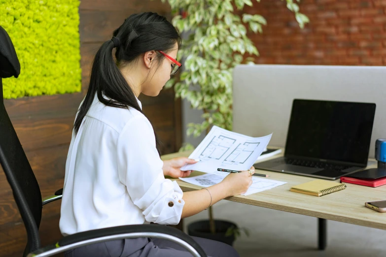 a woman is sitting at her desk and reading a paper