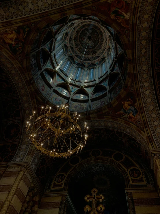 a chandelier hanging from a dome in a very old church