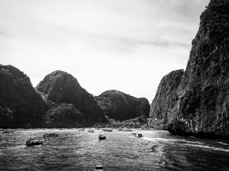 several small boats on the water between two mountains