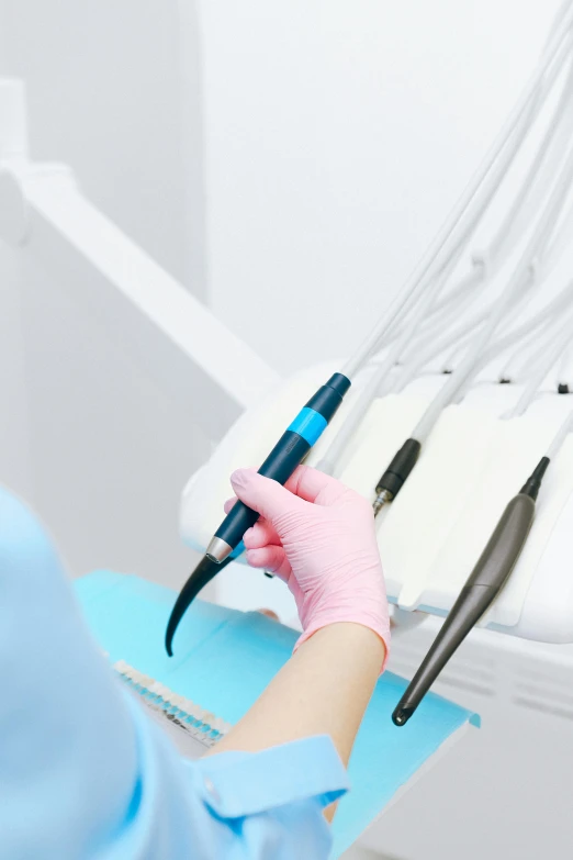 a person with surgical gloves holding a blue pen