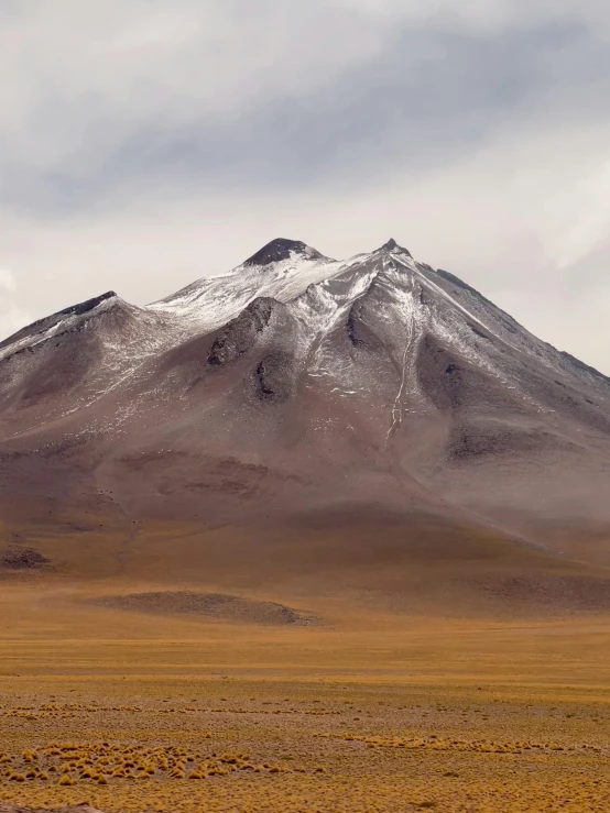 a brown mountain with snow covered top