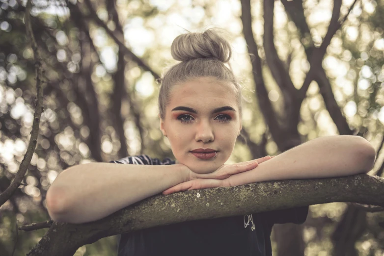 a young woman leaning on a nch in a forest