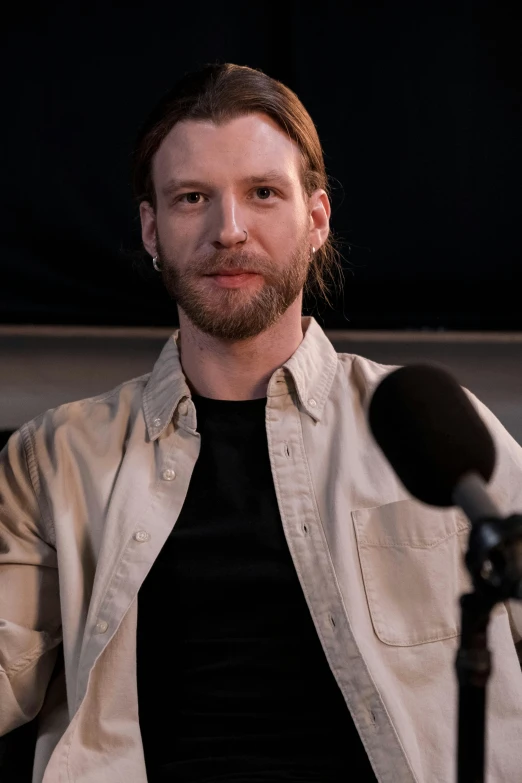 a man in black shirt sitting in front of a microphone