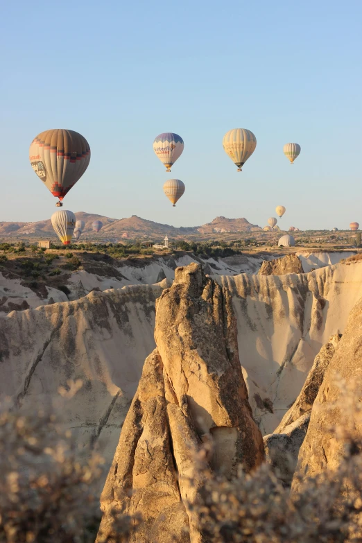 many balloons are flying over some rocks