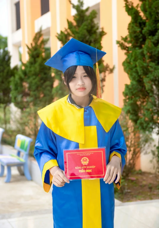 an asian woman in graduation clothes, holding her diploma