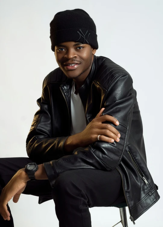 a man sitting on a chair wearing a black jacket