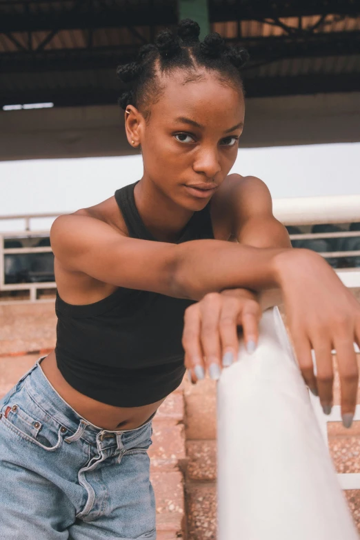 a girl is leaning on a pole next to a wall