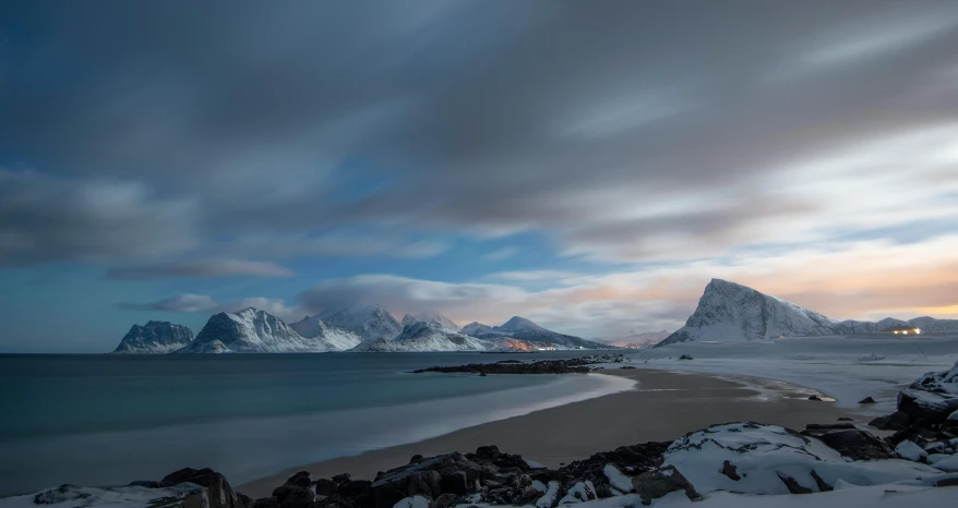 a cloudy sky over the ocean with mountains in the background