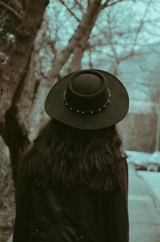 a woman in a hat standing on a sidewalk