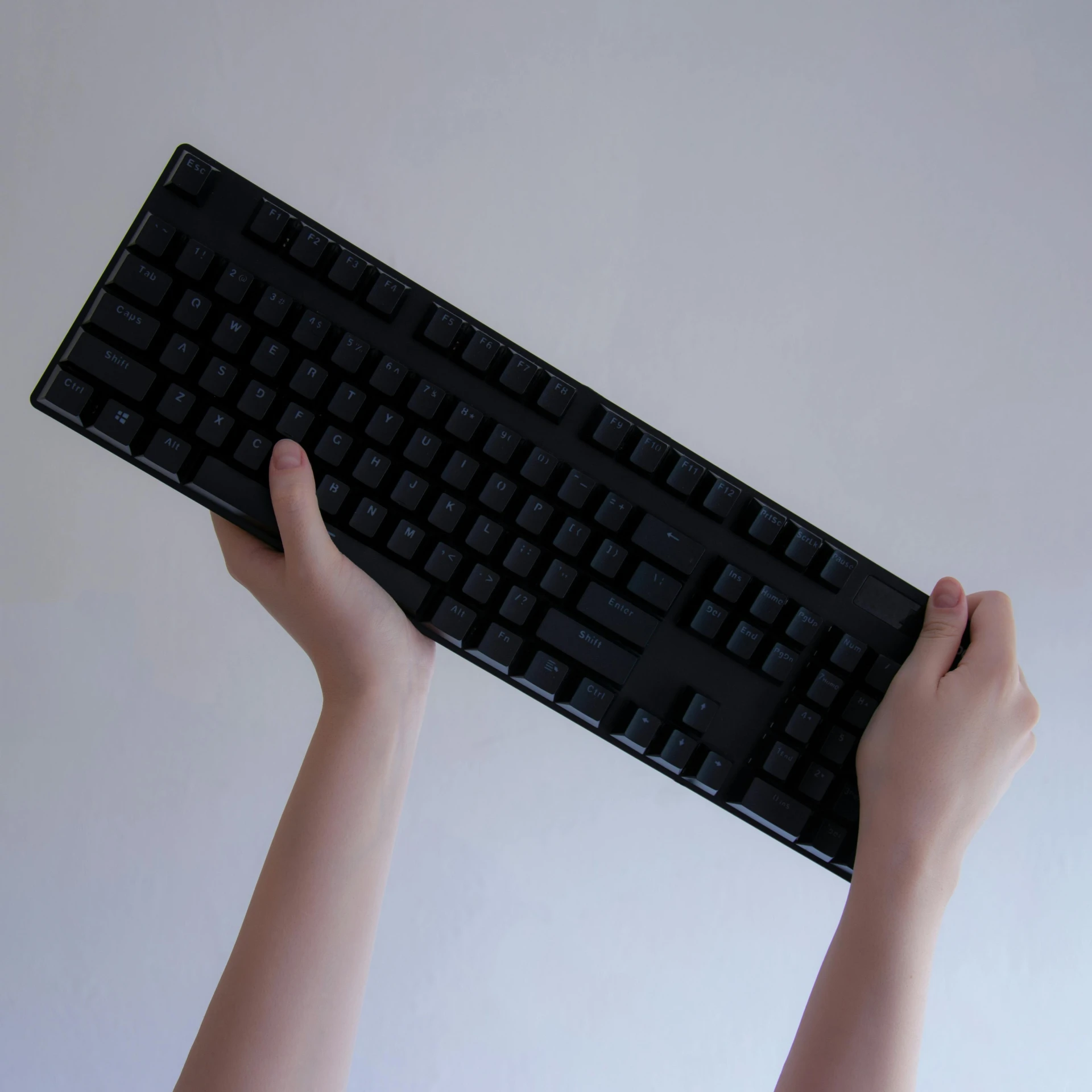 a person that is holding a keyboard over their head