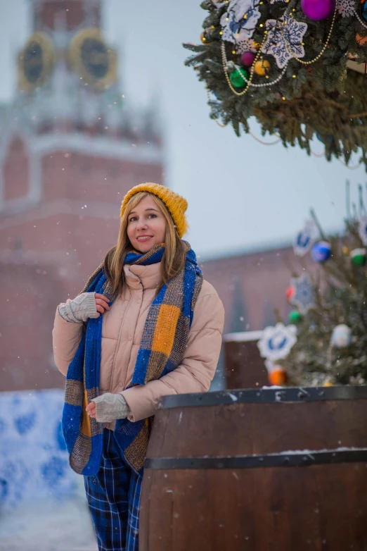 the woman is dressed in warm clothing in front of a christmas tree
