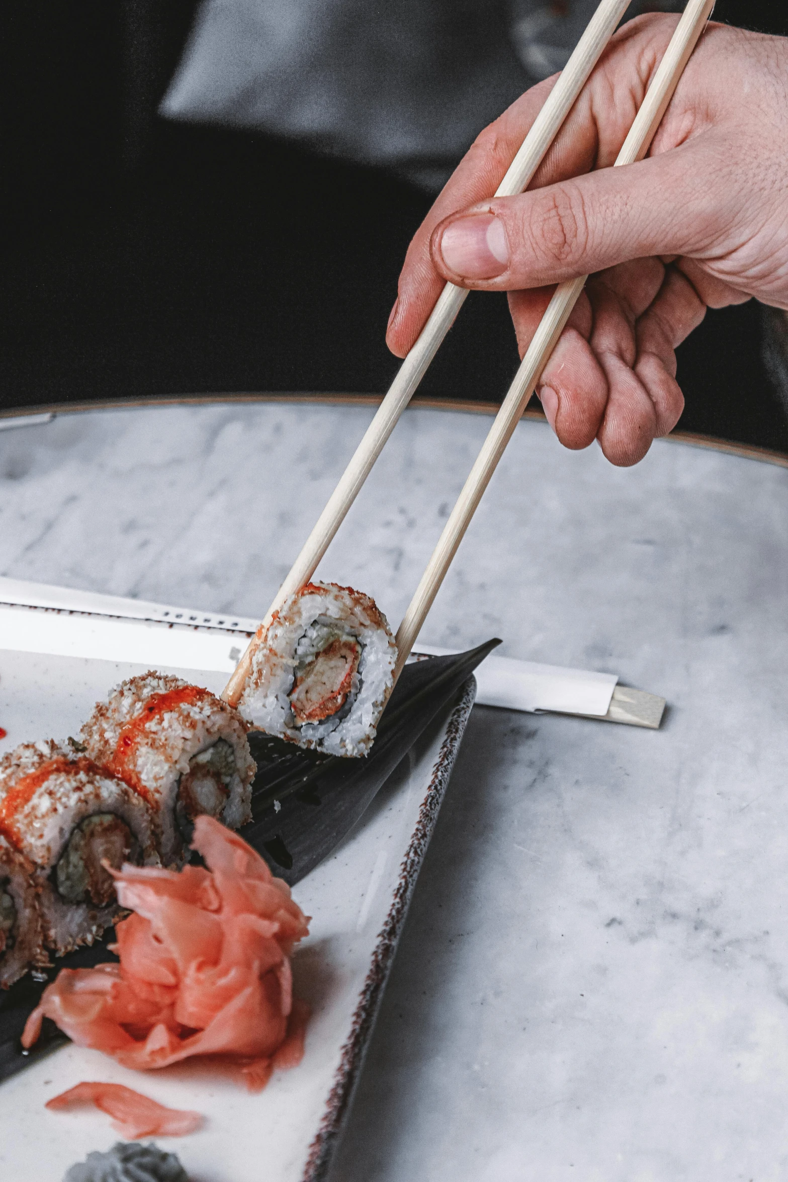 sushi being served on an asian plate by two chopsticks