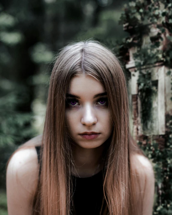 a girl with long hair sitting on the ground near a tree