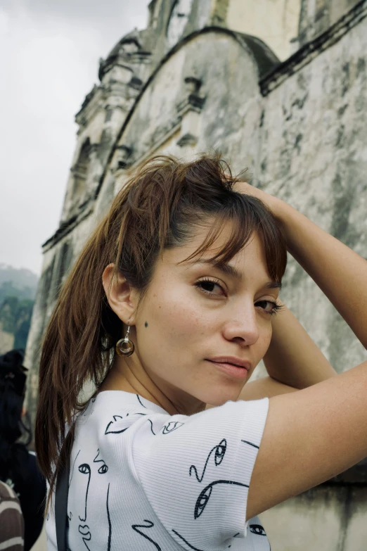 a woman looks intently into the distance next to an old wall